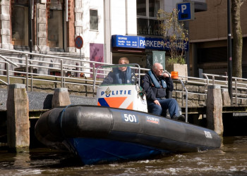 Полицейский катер на канале реки в Амстердаме, Нидерланды – фотографии Нидерландов